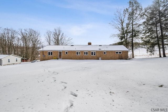 snow covered house featuring a chimney