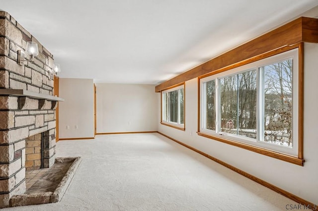 unfurnished living room with light carpet, a fireplace, and baseboards