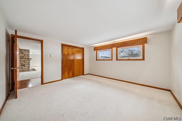 unfurnished bedroom with a closet, light carpet, and baseboards