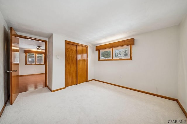 bedroom with baseboards, a closet, and light colored carpet