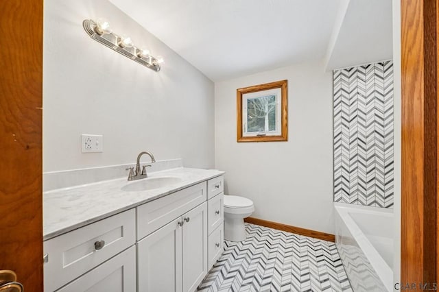 bathroom with baseboards, vanity, toilet, and a bathing tub