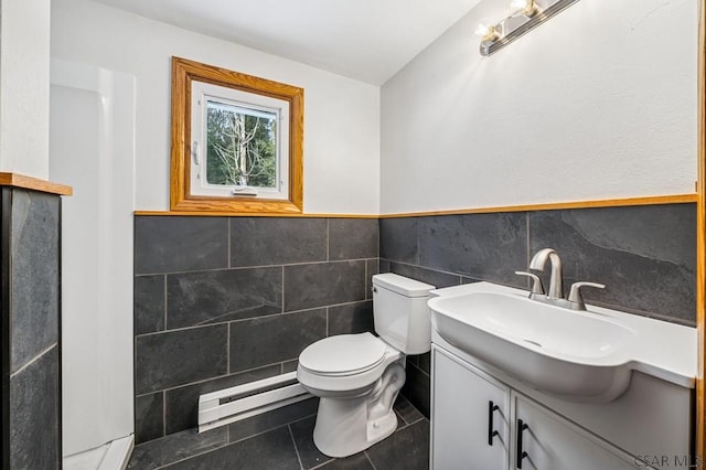 half bathroom featuring tile walls, toilet, baseboard heating, vanity, and tile patterned flooring