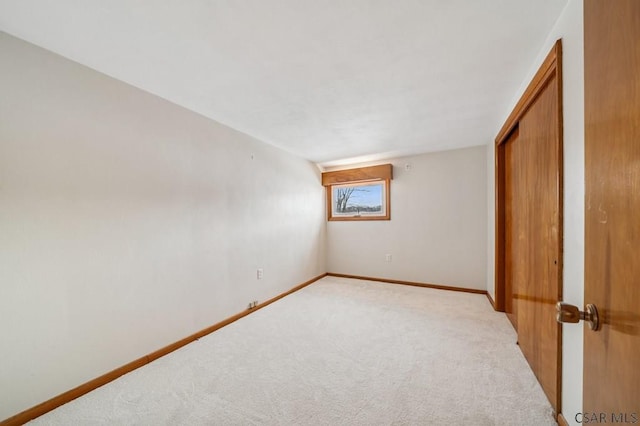 empty room featuring baseboards and light colored carpet