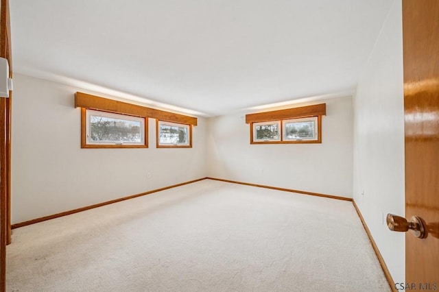 carpeted spare room featuring a healthy amount of sunlight and baseboards