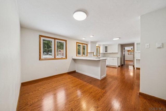 kitchen featuring dark wood-style floors, light countertops, white cabinetry, a peninsula, and baseboards