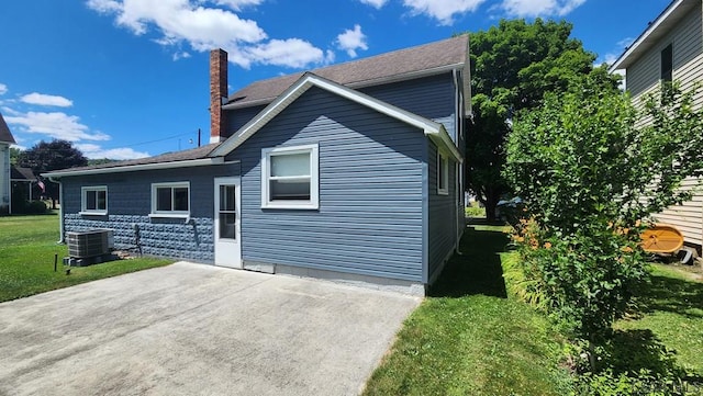 back of house featuring cooling unit and a lawn