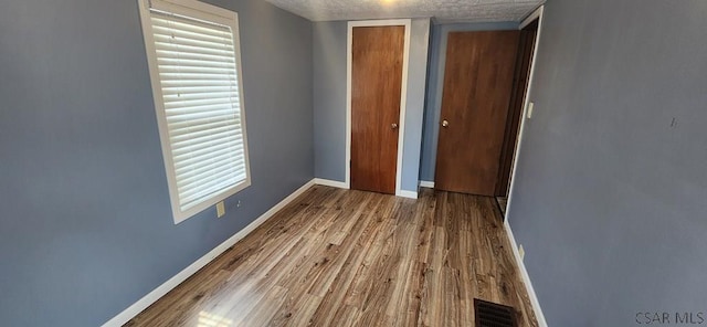 unfurnished bedroom featuring wood-type flooring, a closet, and a textured ceiling