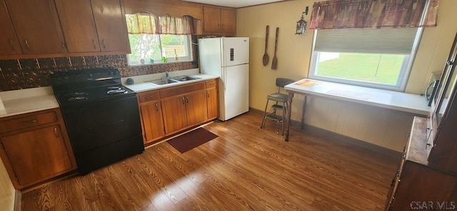 kitchen with sink, black electric range, white fridge, and light wood-type flooring