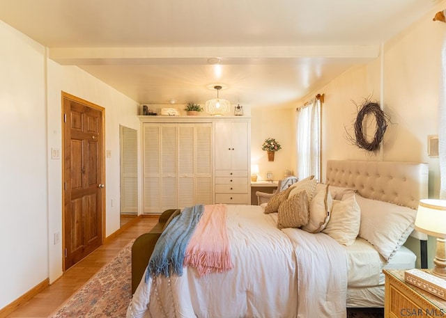 bedroom featuring a closet, beam ceiling, and light hardwood / wood-style flooring