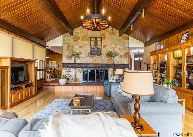 living room with a fireplace, beam ceiling, a chandelier, and light hardwood / wood-style floors