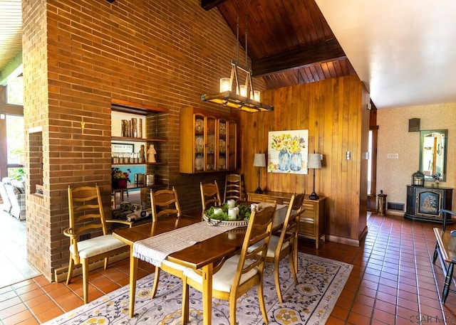 tiled dining room with wood walls, high vaulted ceiling, wooden ceiling, baseboard heating, and beamed ceiling