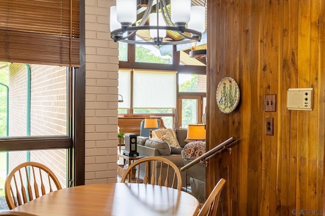 dining space featuring plenty of natural light, an inviting chandelier, and wooden walls