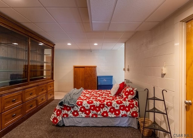 bedroom with a drop ceiling and dark colored carpet