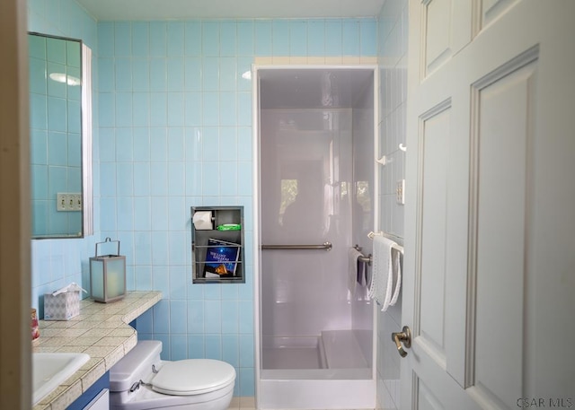 bathroom featuring walk in shower, vanity, toilet, and tile walls