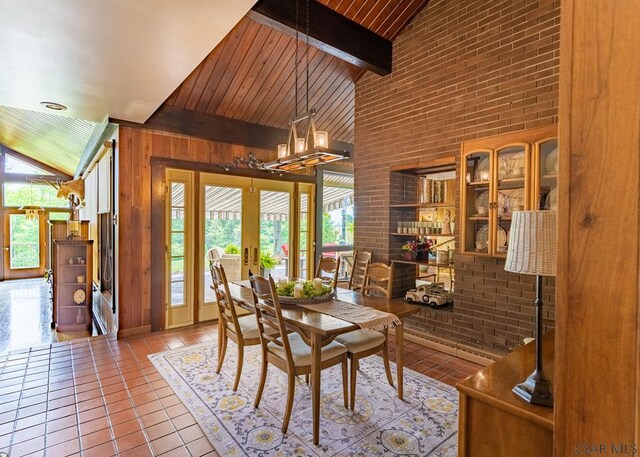 tiled dining space with french doors, high vaulted ceiling, wooden walls, beamed ceiling, and brick wall