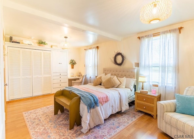 bedroom featuring beamed ceiling and light hardwood / wood-style floors