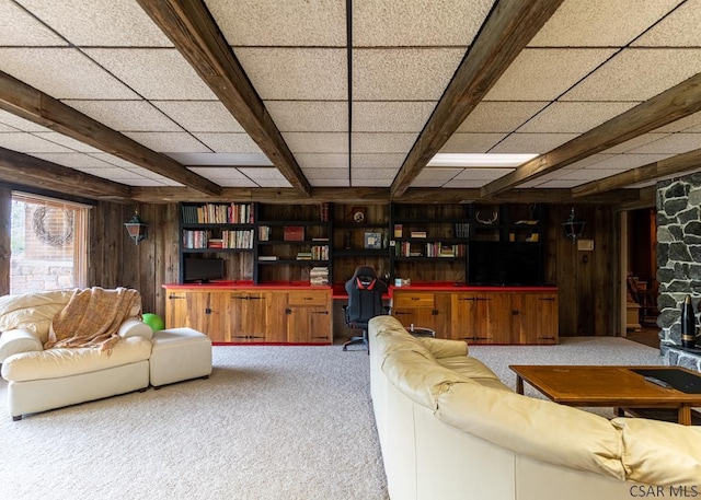 carpeted living room featuring built in desk, a paneled ceiling, and wood walls