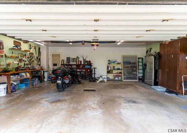 garage with stainless steel fridge with ice dispenser and a workshop area