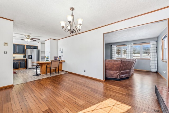 living room featuring ornamental molding, ceiling fan with notable chandelier, a textured ceiling, and light wood-type flooring