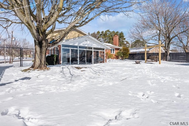 snow covered back of property with a sunroom