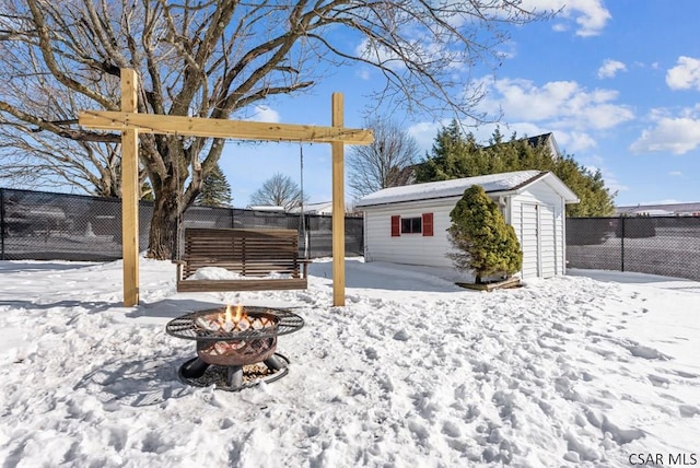 snowy yard with a shed and a fire pit