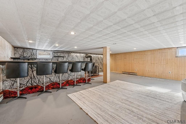 interior space featuring a baseboard heating unit, bar area, and wood walls