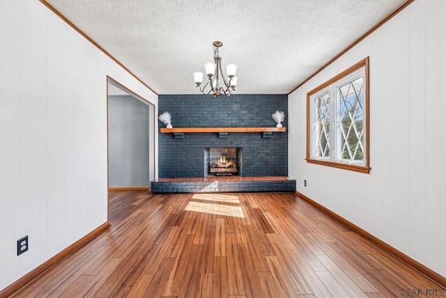 unfurnished living room featuring wood-type flooring, a fireplace, a chandelier, and a textured ceiling