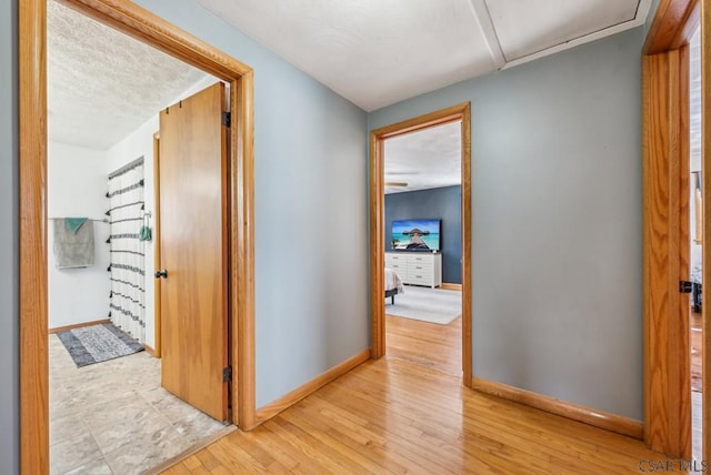 hall with light hardwood / wood-style flooring and a textured ceiling