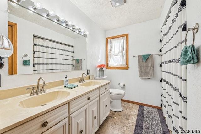 bathroom with vanity, toilet, and a textured ceiling