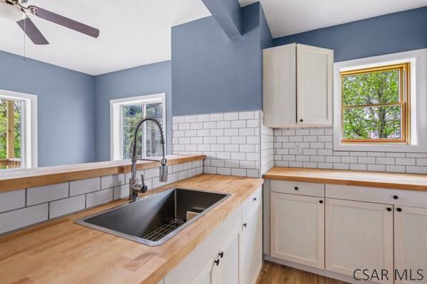 3445 Graham Ave, Windber, PA 15963 - kitchen featuring butcher block counters, backsplash, a ceiling fan, and white cabinets