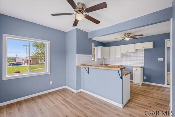 3445 Graham Ave, Windber, PA 15963 - kitchen featuring a ceiling fan, a peninsula, backsplash, white cabinets, and light wood-style flooring
