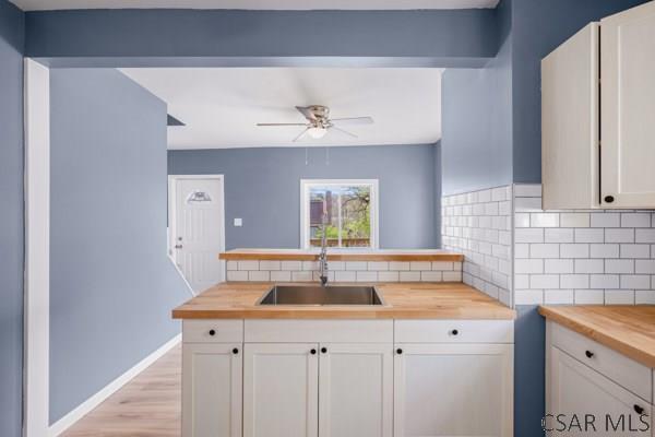 3445 Graham Ave, Windber, PA 15963 - kitchen with butcher block countertops, backsplash, a ceiling fan, white cabinets, and light wood-type flooring