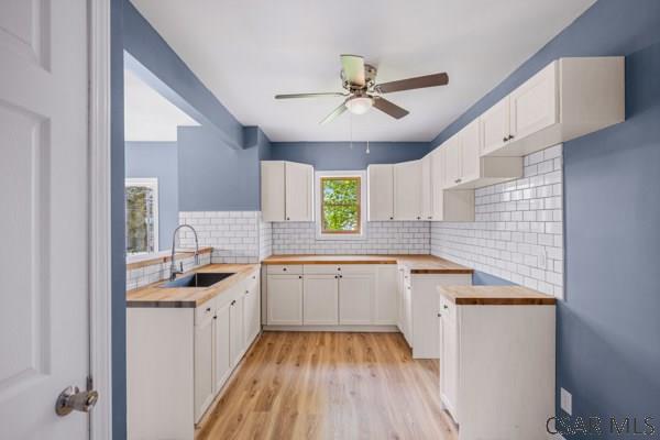 3445 Graham Ave, Windber, PA 15963 - kitchen featuring ceiling fan, tasteful backsplash, light wood-type flooring, and white cabinets