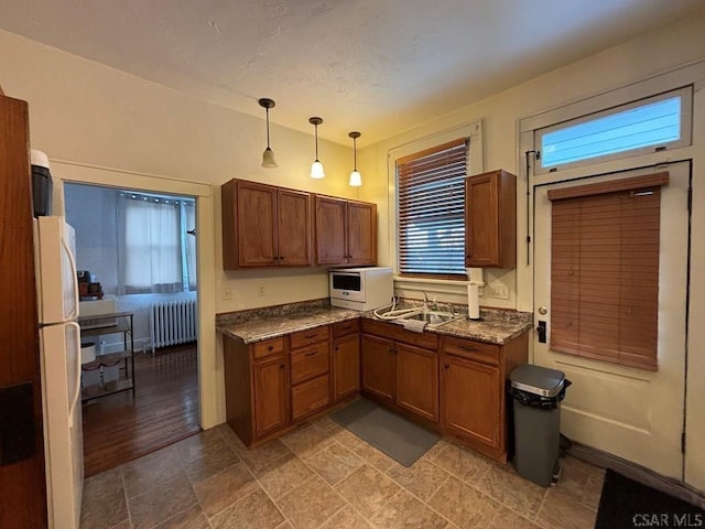 kitchen with sink, decorative light fixtures, white refrigerator, radiator heating unit, and a wealth of natural light