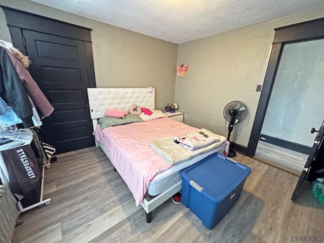 bedroom with a textured ceiling and hardwood / wood-style floors