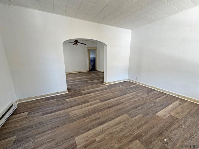 spare room with a baseboard heating unit, ceiling fan, and dark hardwood / wood-style flooring