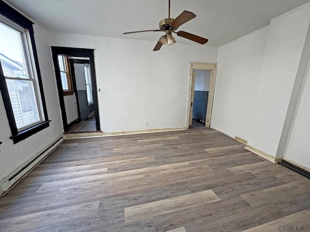 spare room featuring baseboard heating, ceiling fan, and hardwood / wood-style flooring