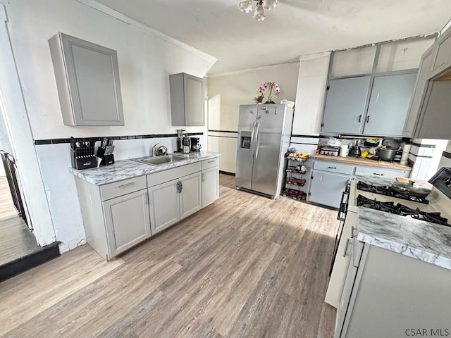 kitchen with light hardwood / wood-style flooring, sink, gray cabinetry, and stainless steel fridge with ice dispenser