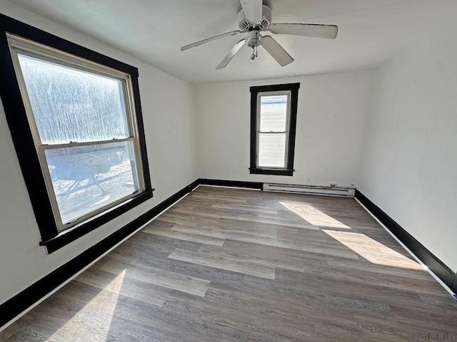 spare room with light wood-type flooring, ceiling fan, and baseboard heating