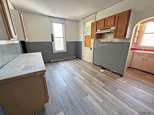 kitchen with light hardwood / wood-style flooring, decorative backsplash, and baseboard heating