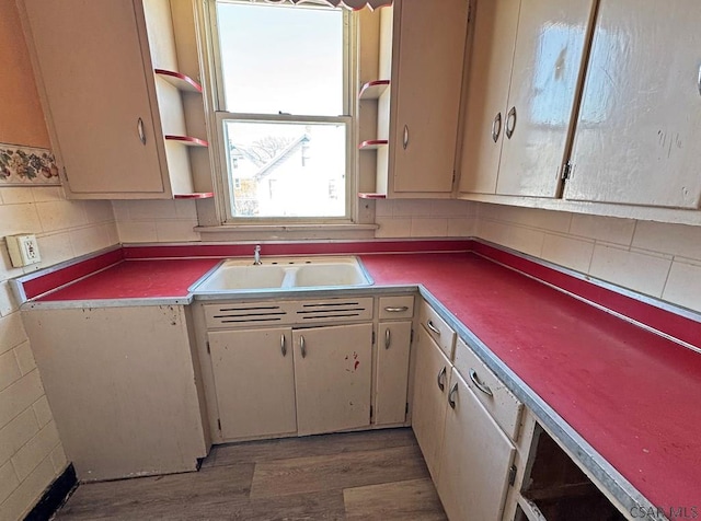 kitchen with sink, hardwood / wood-style flooring, cream cabinetry, and decorative backsplash