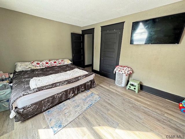 bedroom with a textured ceiling and wood-type flooring