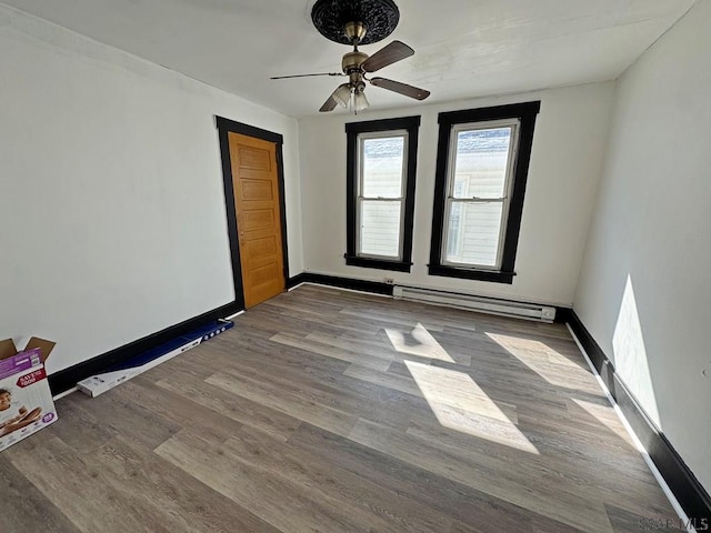 unfurnished room featuring hardwood / wood-style flooring, ceiling fan, and a baseboard radiator