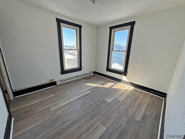 unfurnished room with dark hardwood / wood-style flooring, a baseboard heating unit, and a textured ceiling