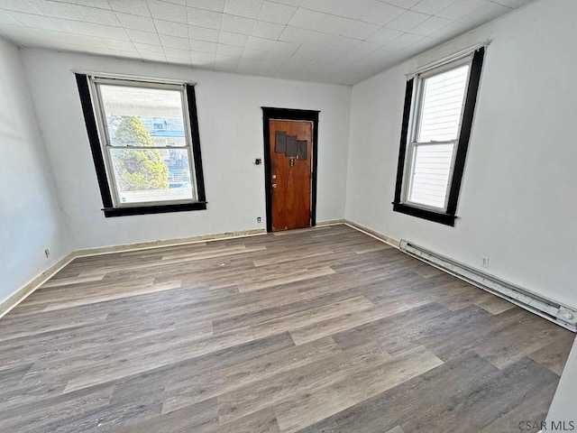 empty room featuring light hardwood / wood-style floors and a baseboard heating unit