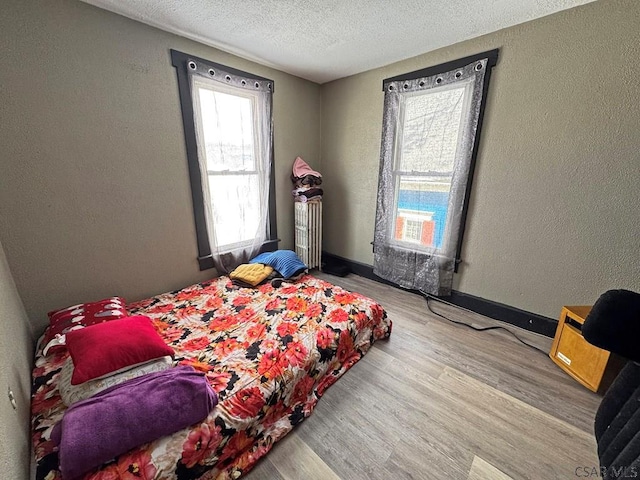 bedroom with a textured ceiling and wood-type flooring