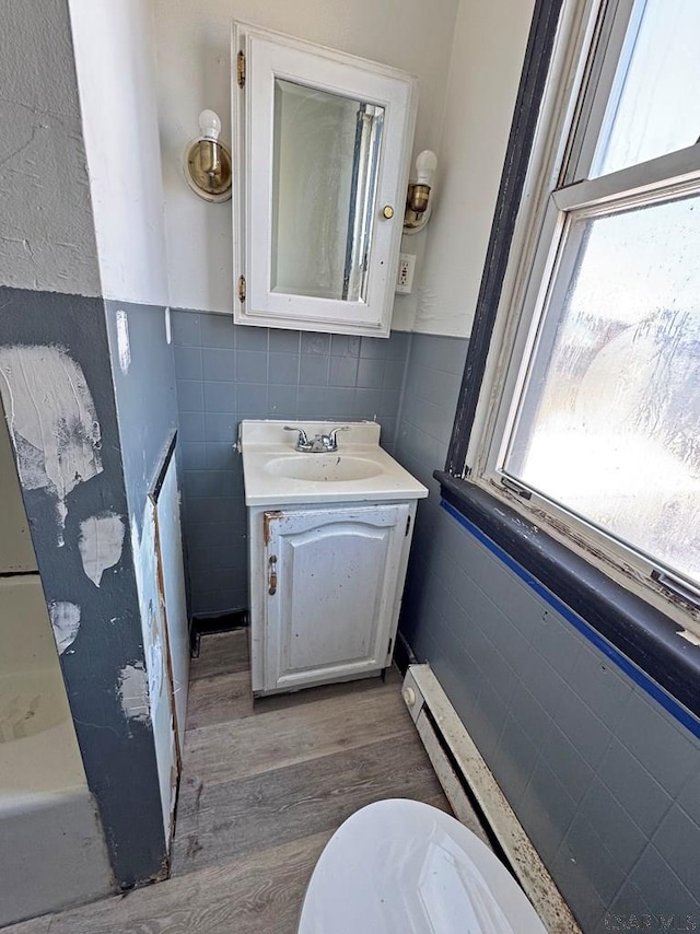 bathroom featuring toilet, tile walls, wood-type flooring, and vanity