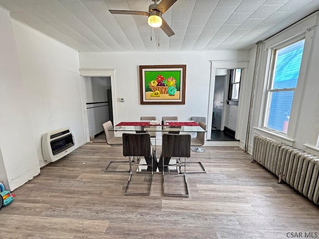 dining space with heating unit, radiator, light wood-type flooring, and ceiling fan