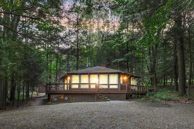 back house at dusk featuring a wooden deck