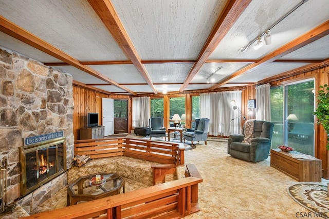 living room with a stone fireplace, wooden walls, beamed ceiling, carpet flooring, and coffered ceiling